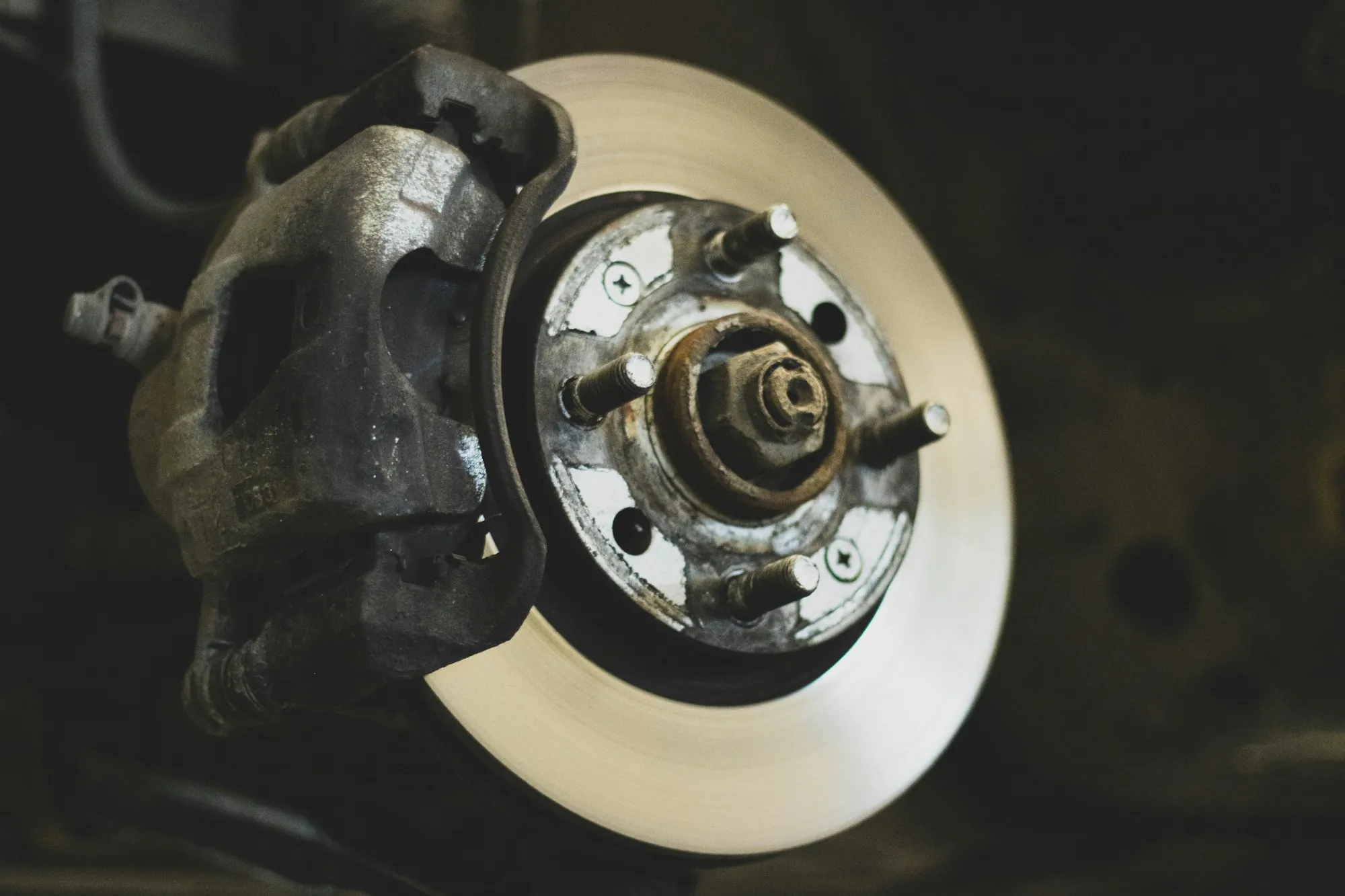Close view of a brake caliper and rotor on a raised vehicle