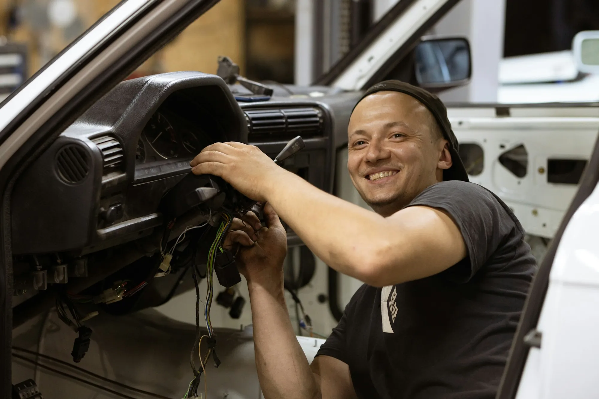 Smiling technician working behind the dashboard of a vehicle