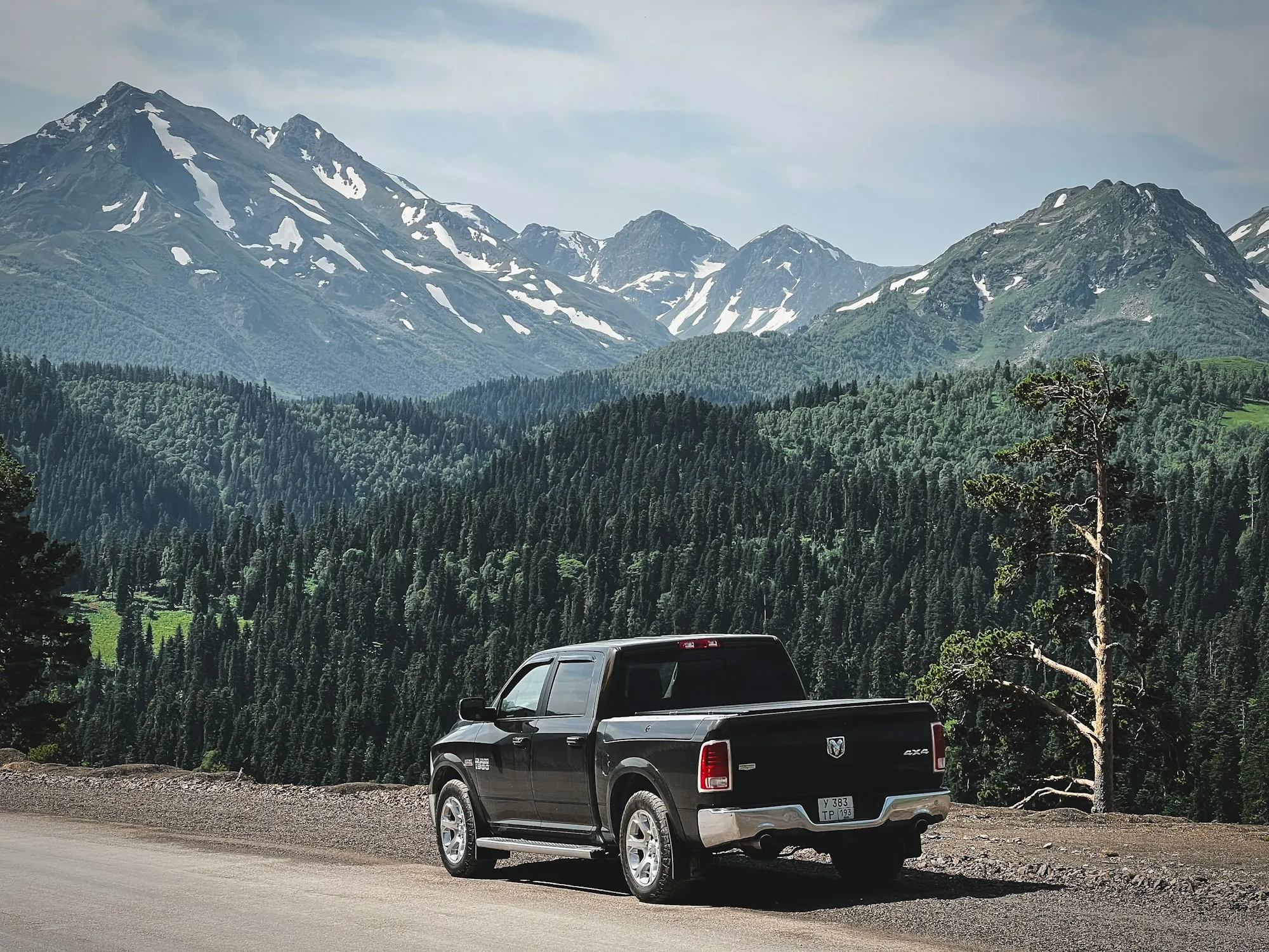 Black pickup parked below forested mountains