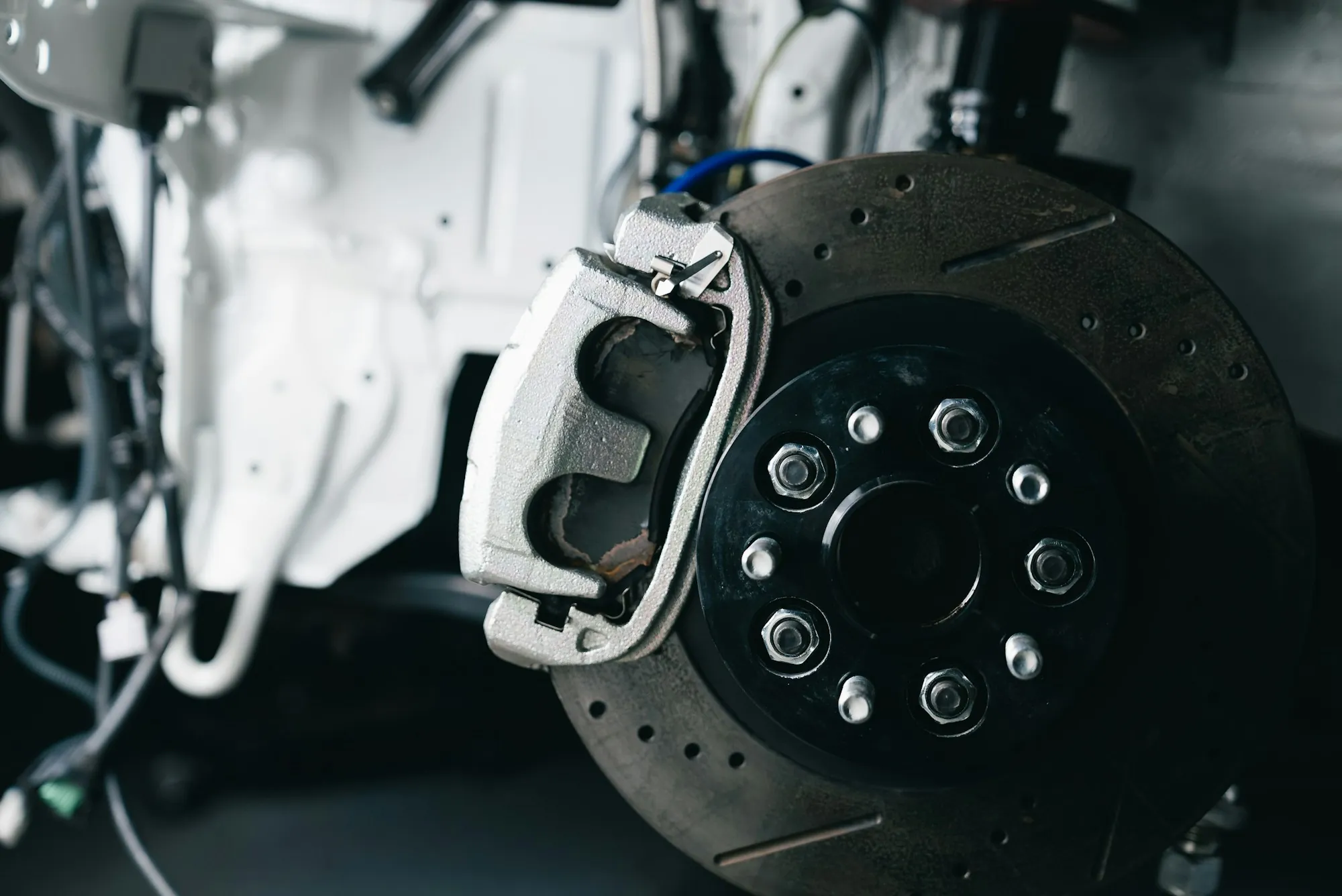 Drilled brake rotor and caliper on a vehicle on the lift