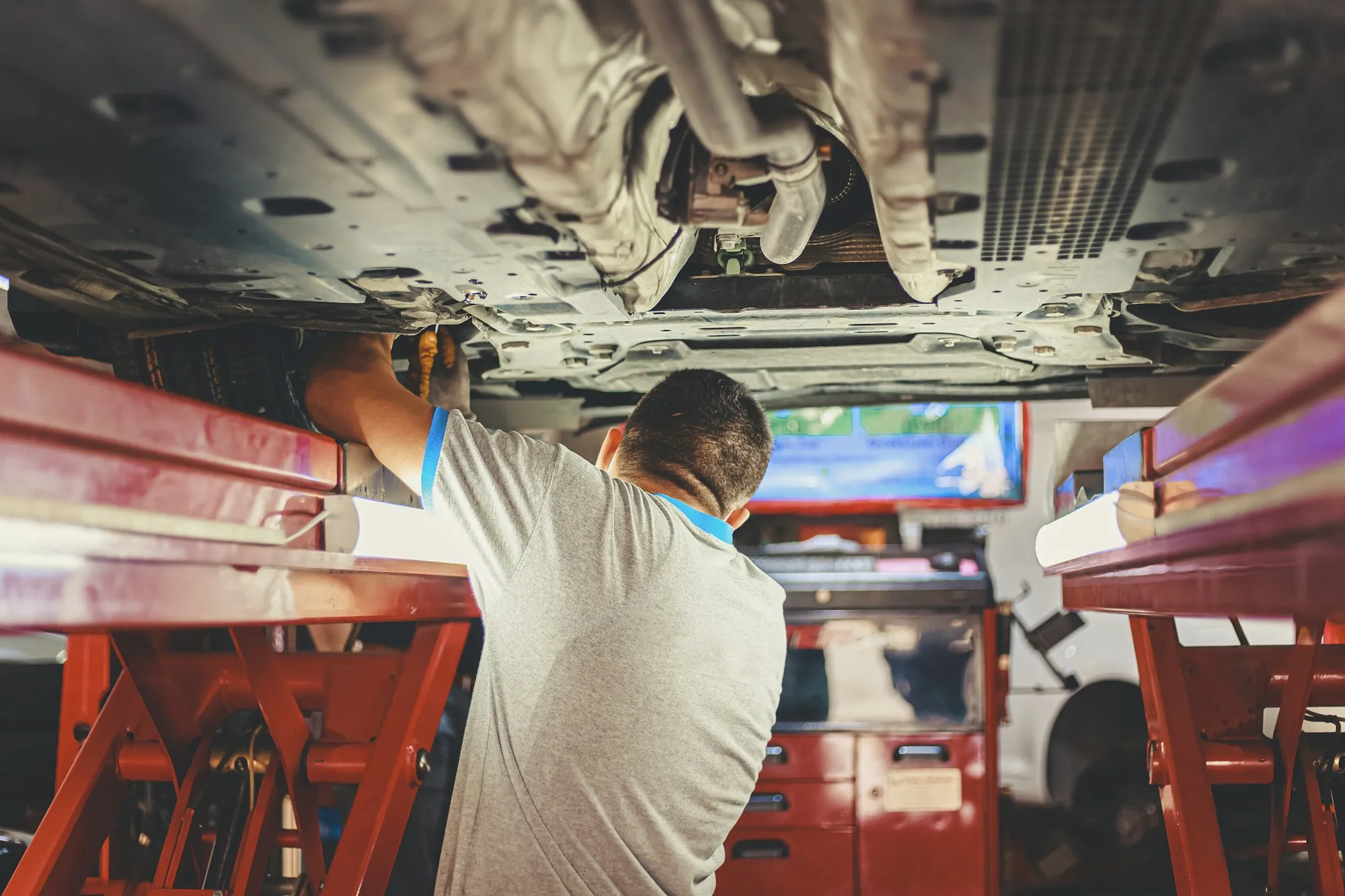 Technician inspecting the underside of a vehicle on a lift