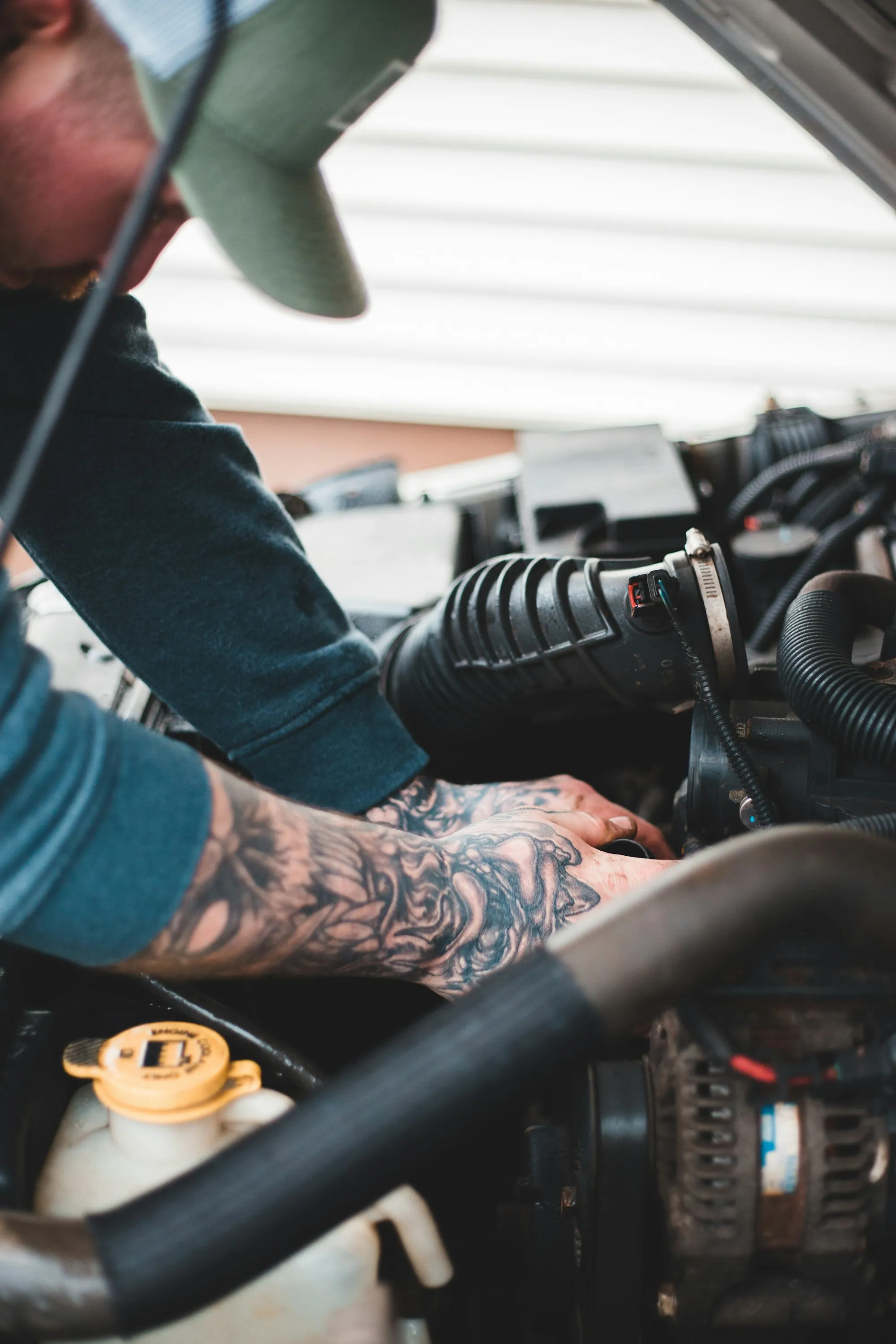 Technician's hands working a fitting deep in an engine compartment
