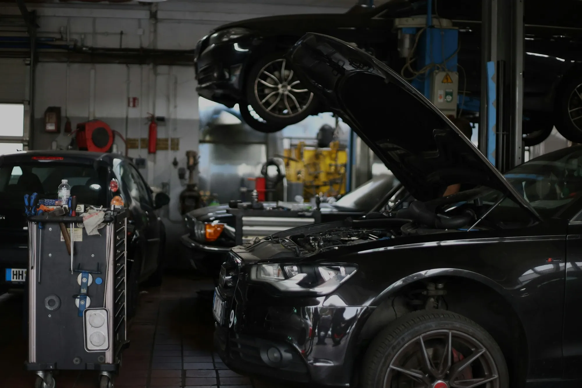 Repair shop with a car raised on a lift and a diagnostic cart nearby