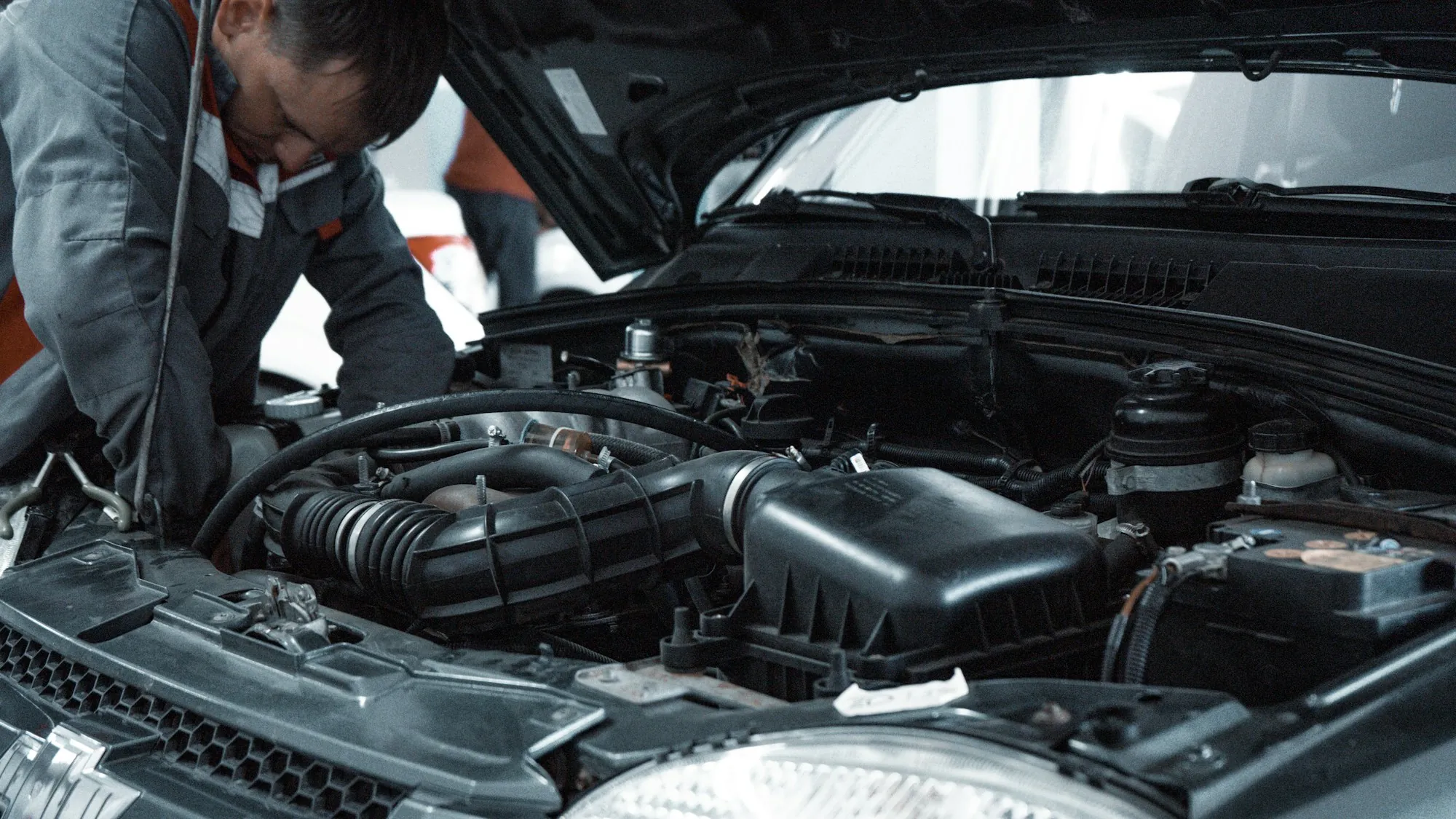 Two technicians leaning into an open engine bay to trace a fault