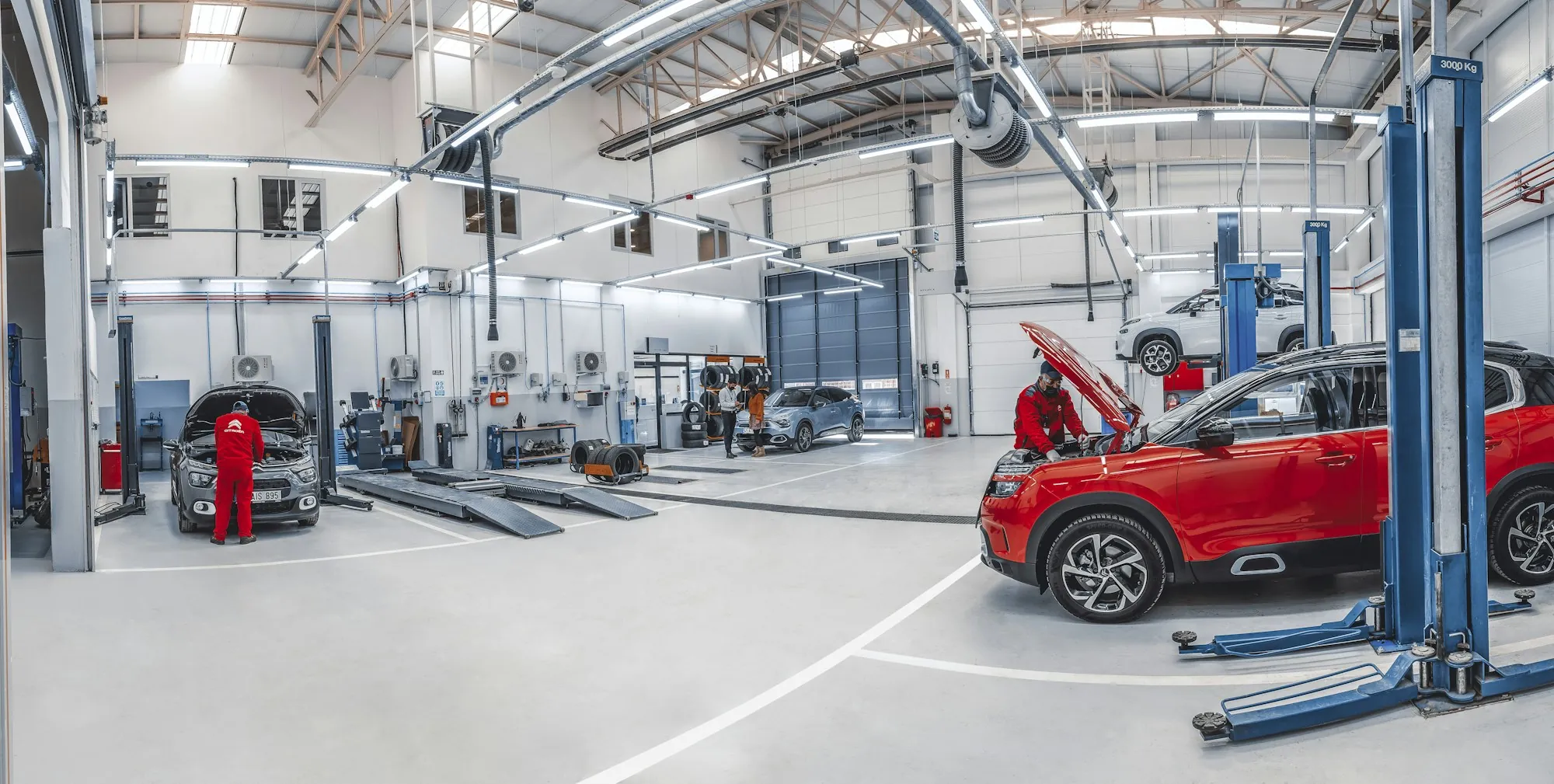 Bright repair shop with vehicles raised on two-post lifts